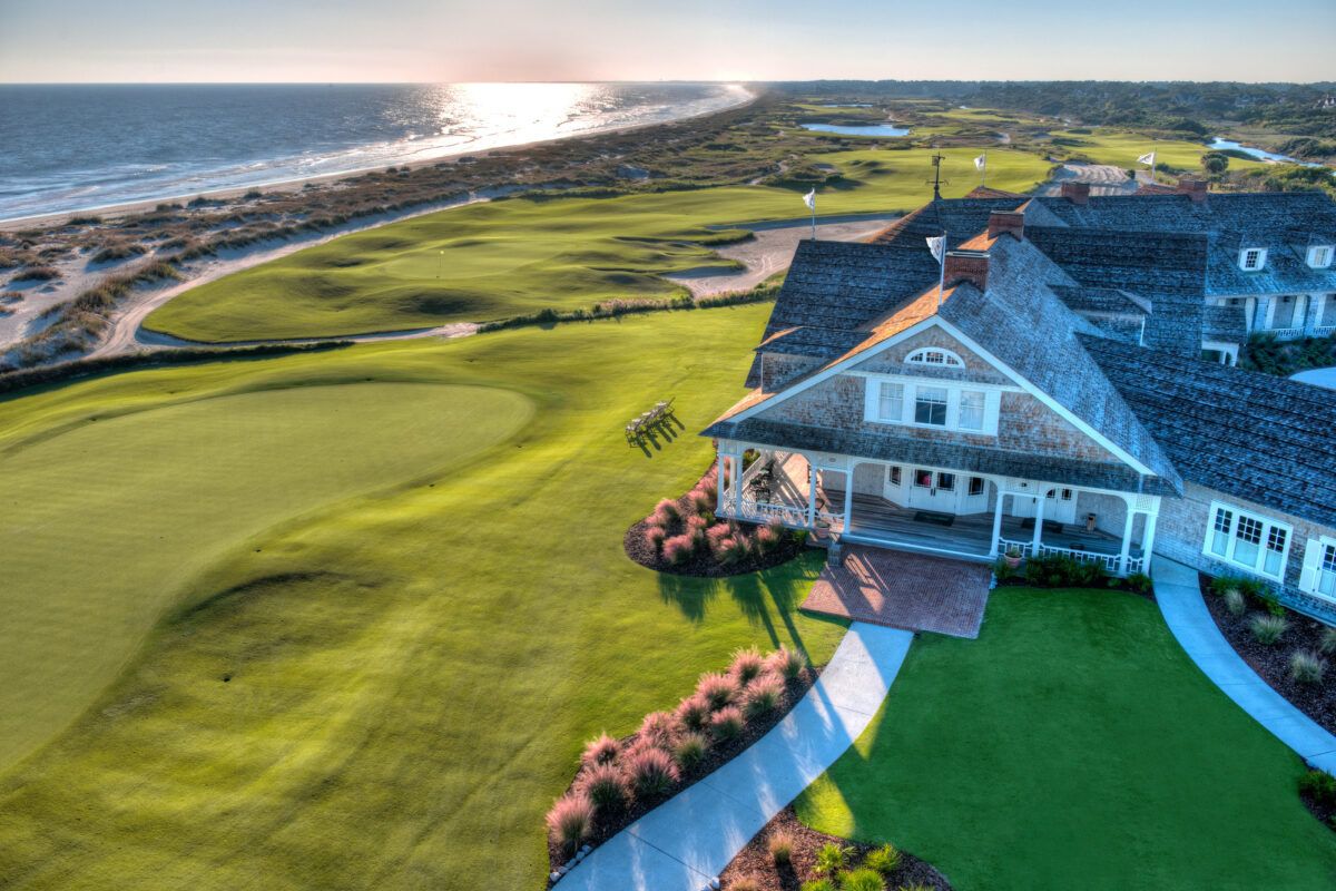 Golf course with a clubhouse by the ocean during sunset