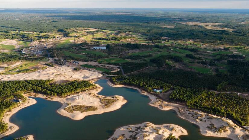 Aerial view of a lake surrounded by greenery and construction sites.